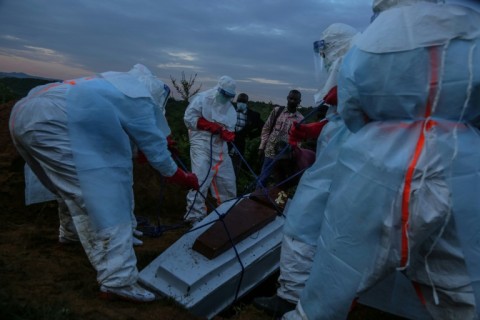 Medical staff in full hazard gear bury a suspected Ebola patient who died at the hospital in Rwampara