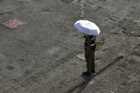 A member of the security forces shelters from the sun under an umbrella in Mina near Mecca