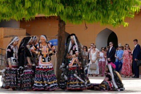 Artists wearing traditional attire and members of US Secretary of State Marco Rubio's team wait in the shade as he tours the Amber Fort in Jaipur