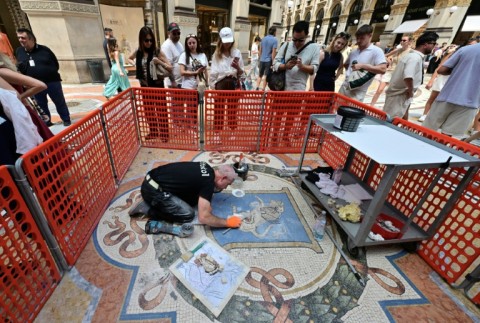 Restorer Gianluca Galli works on the mosaic of the bull during the restoration in the Galleria Vittorio Emanuele II