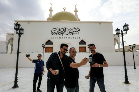 People pose for a group selfie outside the Sahaba Mosque in Derna