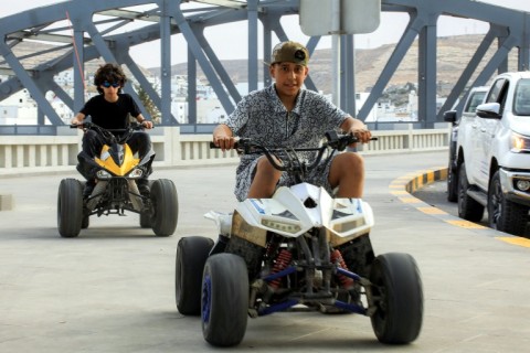 Children ride all-terrain vehicles (ATVs) along a pedestrian pavement in Derna