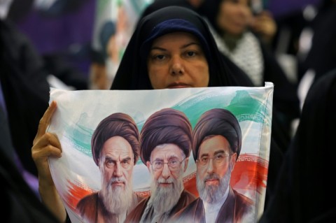 An Iranian woman holds an image of former and the current Iranian supreme leaders in Tehran