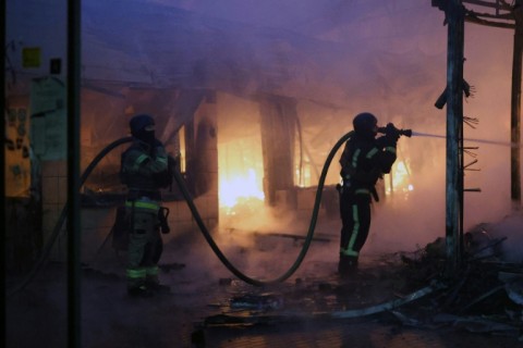 Firefighters put out a blaze at a market during the Russian missile strike on the Ukrainian capital of Kyiv