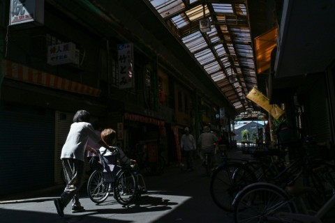 An elderly woman (2nd L) being pushed through the Tsurumibashi "shotengai", an old covered shopping street in the Nishinari ward of Osaka