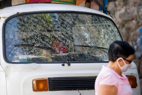 A woman walks past a van riddled with bullet holes during a police operation in the Santa Marta favela