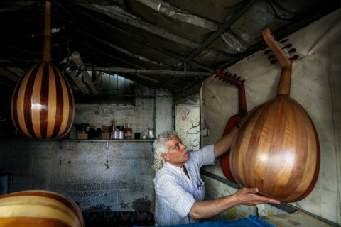 Displaced Palestinian craftsman Suhail Abu Shawish repairs damaged Ouds at a workship in Nuseirat refugee camp in Gaza