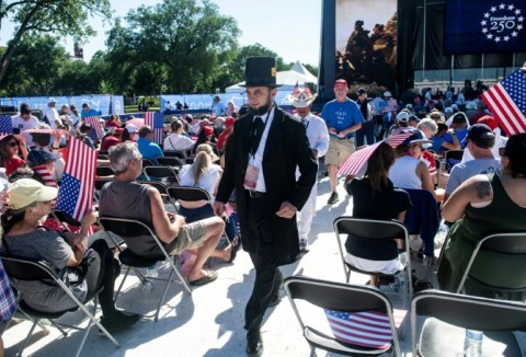 An attendee dressed as Abraham Lincoln walks through the crowd during a kick-off celebration for the 'Great American State Fair' on the National Mall in Washington