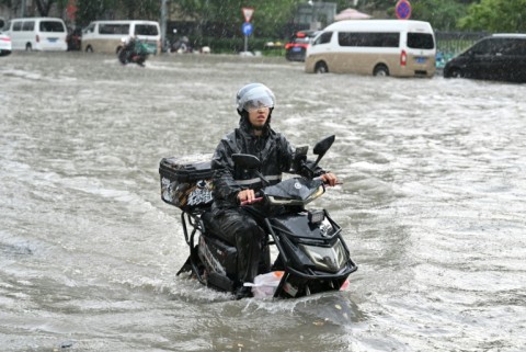 A man on a scooter makes his way along a flooded street in Beijing
