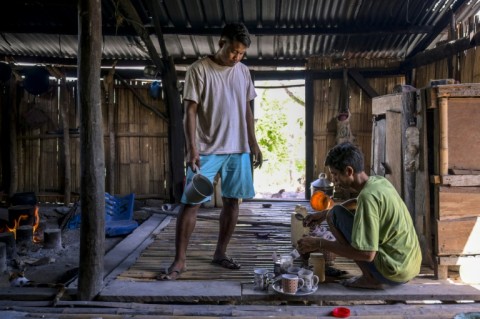Nobleman Umbu Ana Rara (left) watches as his slave Kanisius Kanyali Hambarita prepares tea