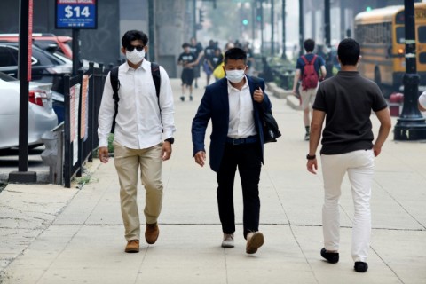 People wear face masks while walking through downtown Chicago as smoke from wildfires burning in Canada blankets the Chicago metropolitan area on July 16, 2026