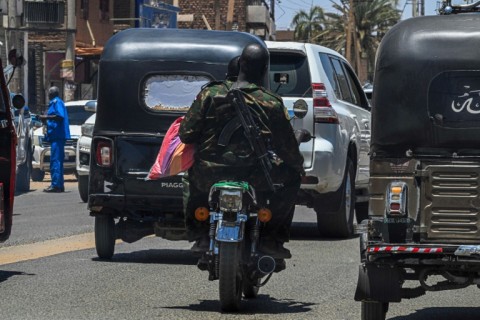 A Sudanese army soldier carries Kalashnikov while riding a motorcycle along the street in Khartoum in April