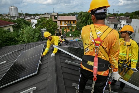 Workers install solar panels on a roof in Carmona, in the Philippine province of Cavite