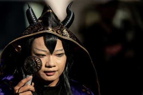 A cosplayer uses a portable fan to cool down while visiting the Osu Shopping Street before the Osu Cosplay Parade, during the second day of the World Cosplay Summit 2026 in Nagoya on August 1, 2026.