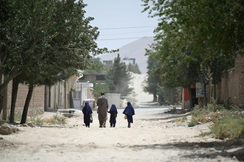 A father brings his daughters to primary school in Kabul
