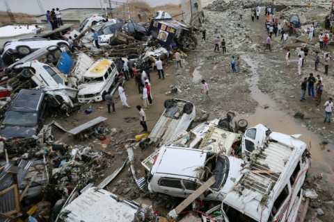 Residents look at damaged vehicles after flash flood and landslide triggered by heavy rains wreaked havoc at Rajouri district in India's Jammu region on July 19, 2026
