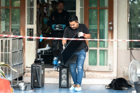 Officials carry a computer out of the house where a teenager is suspected of killing his grandparents before carrying out a school shooting north of Thailand's capital Bangkok.