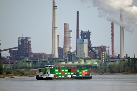 A cargo ship passes an industrial site on the Rhine
