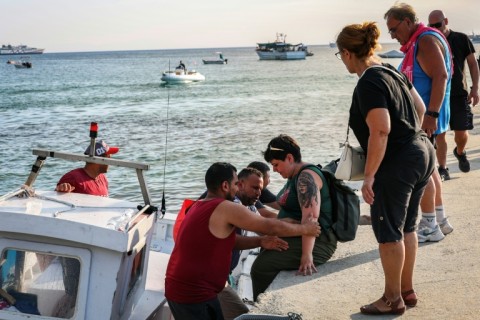 People climb onto small boats as they flee a wildfire near the village of Siviri, northern Greece