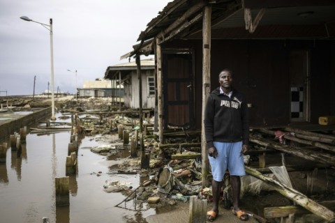 Augustin Edward, 30, carpenter, stands outside his destroyed home