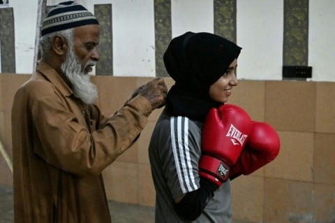 A coach helps his student Hoorain Zahra fix her scarf during a training session in Karachi