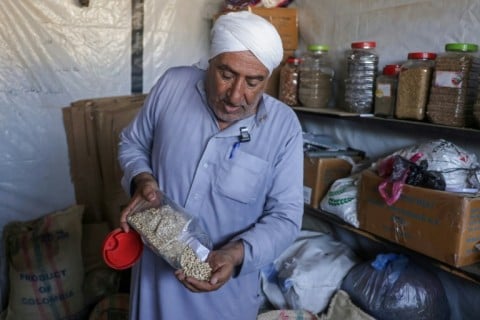 Salem Muhanna, who manages the Al Qarara Seed Bank with support from the ICRC, displays white cowpea seeds at the bank, in Deir el-Balah, central Gaza Strip