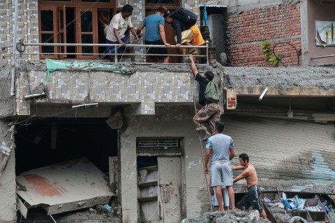 Residents climb up to their house to search for belongings at the Dhunge Bazaar in Nepal's Nuwakot district
