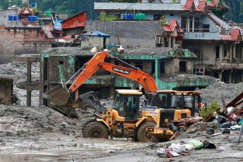 Workers use excavators to clear the mud at the Dhunge Bazaar in Nepal's Nuwakot district on August 29, 2026 after flash floods