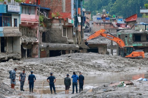 Workers use excavators to clear the mud at the Dhunge Bazaar in Nepal's Nuwakot district on August 29, 2026