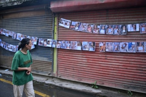 A woman looks at photographs of the missing and dead following flash floods in Nepal, outside a hospital in Kathmandu