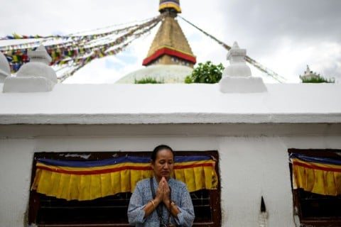 A woman offers prayers during a vigil to pay tribute to the flash flood victims at the Boudhanath Stupa in Kathmandu