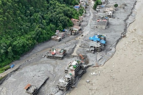 A torrent of muddy water surging past houses and through the Trishuli River in the aftermath of flash floods at Trishuli Center in Nepal