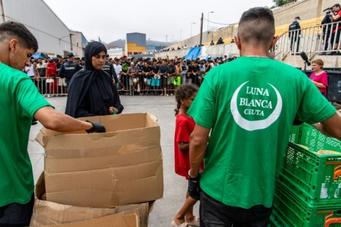 Migrants queue for hours every day to receive food from NGOs