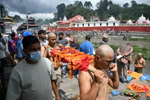 Relatives carry Kush grass effigies for cremation in accordance with Nepali Hindu rites during symbolic funerals held for flood victims