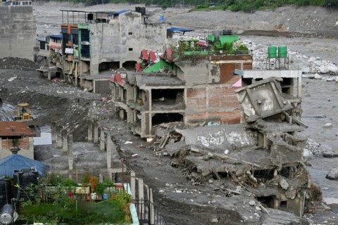 A man using an excavator clears sludge along the Trishuli river in the aftermath of flash floods at Trishuli Bazar in Nepal's Nuwakot district on September 5, 2026