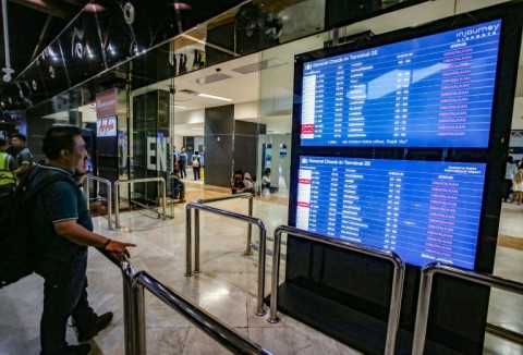 A stranded passenger looks at the departure board for the status of flights at Soekarno-Hatta Airport in Tangerang