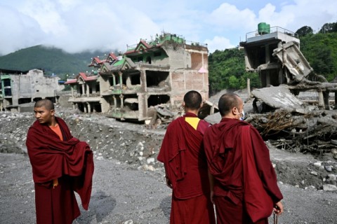 Buddhist monks look at destroyed buildings in Nepal's Trishuli, as the country marked a day of mourning after devastating August 26 floods