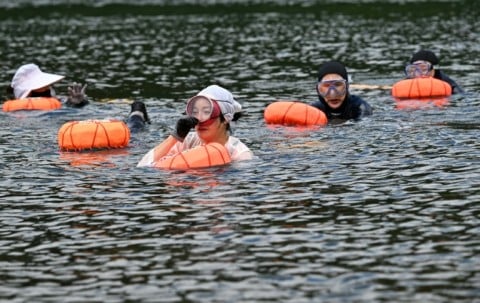 Participants swim using the tewak, a buoy used by haenyeo floating, during a haenyeo training session in the South Korean coastal town of Geoje