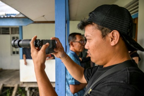 A Borneo Future Indonesia observer tries out a special mobile phone telephoto lens for observing wildlife in Labian village in Kapuas Hulu, West Kalimantan