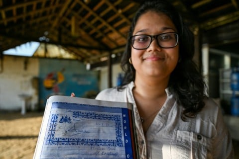Beach Wadiya co-owner Suhara Chandrasekera displays the signature of Britain's Princess Anne, a former customer, in a guest book. Chandrasekera says the restaurant has business permits that predate the 1981 law being used to evict them.