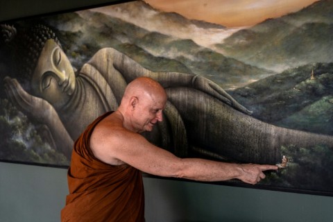 British and Thai Buddhist monk Shaun Chiverton, now known as Ajahn Jayasaro, points to a painted figure representing himself in a depiction of Buddha