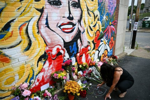 A woman writes the initials of Dolly Parton in chalk as she visits a mural of Parton in Nashville, Tennessee, on August 26, 2026