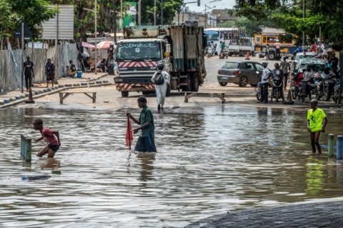 Children wade through a flooded street in Dakar, on October 5, 2026
