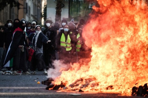 Protesters stand behind a fire during clashes prior to the start of a demonstration in Marseille