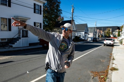 Jake Fortes, a resident whose property sits on the fenceline, less than 100 feet from diesel generators, of the Markley Lowell Data Center, points to high power lines running over streets and sidewalks in Lowell