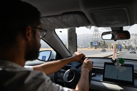 Ahmed Al-Lahham, a driver for ride-hailing application "Yalla Go!", drives his plug-in hybrid vehicle (PHEV) in Damascus
