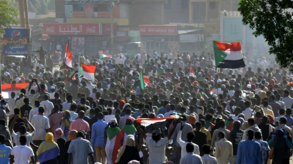 Sudanese protesters lift national flags during a November 21  demonstration in the capital's twin city of Omdurman