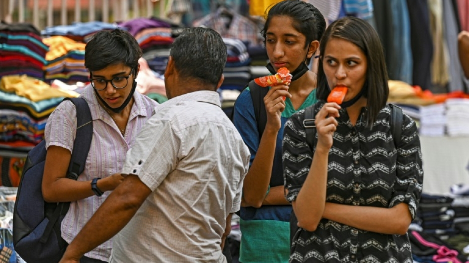 Girls eat ice lollies while shopping on a hot summer afternoon in New Delhi