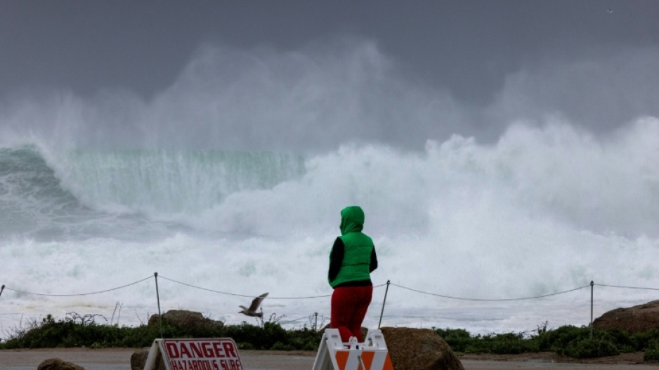 A person watches dangerously large surf hitting California's Monterey Peninsula on January 13, 2023 as the US state braced for the latest in a weeks-long series of powerful storms 