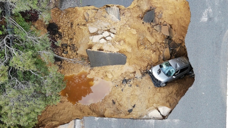This aerial view shows two cars siting in a large sinkhole that opened during a day of relentless rain, January 10, 2023 in the Chatsworth neighborhood of Los Angeles, California